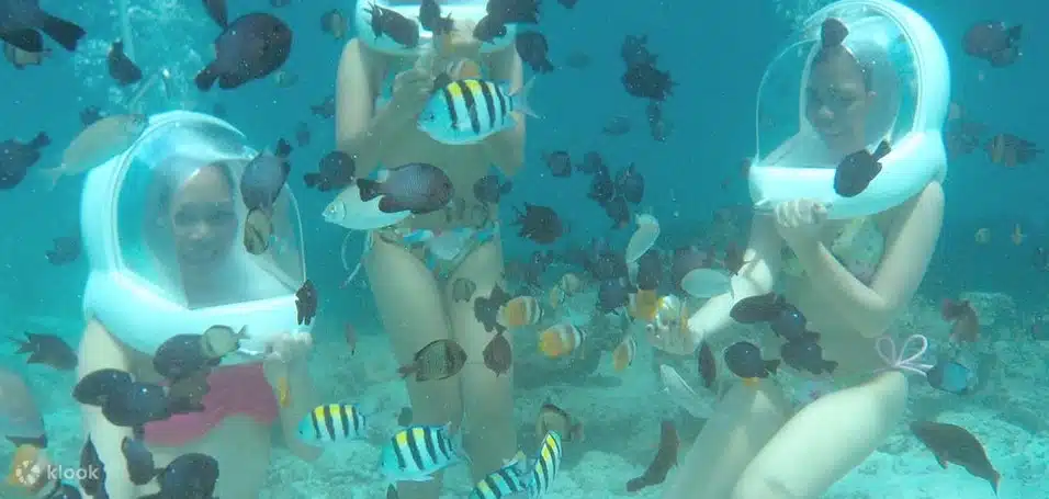 3 women helmet diving in Boracay with schools of fish and corals